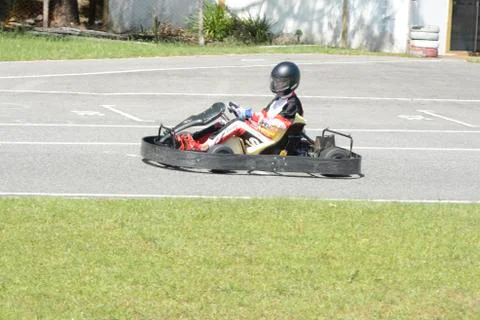 Side view of go-kart driver driving on race track on sunny day Stock Photos