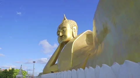 Side view of golden reclining Buddha statue with moving clouds Stockbeeldmateriaal 337519456