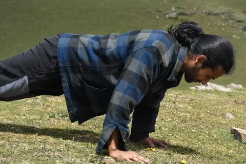 Side view of a good looking Indian young man with ponytail hair style doing push Stock Photos