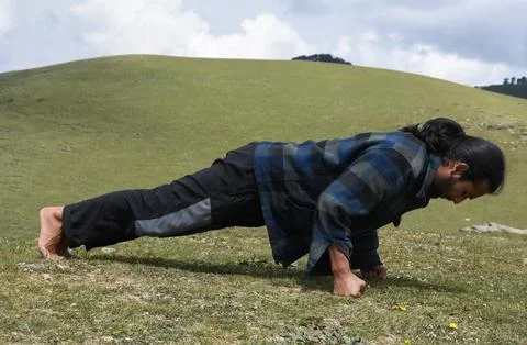 Side view of a good looking Indian young man doing fist push-ups in the mountain 写真素材