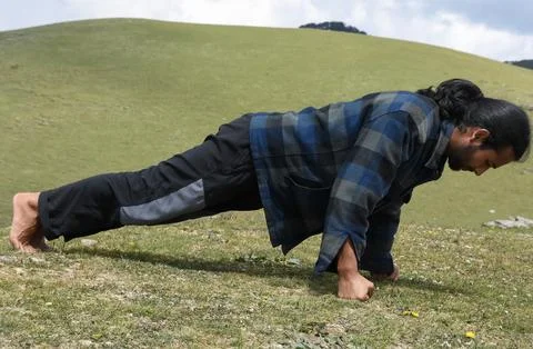 Side view of a good looking Indian young man doing fist push-ups in the mountain Stock Photos