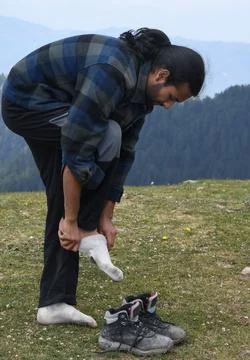 Side view of a good looking Indian young man bending forward to wear socks  Stock Photos