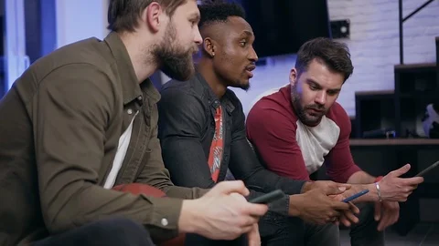 Side view of good-looking serious modern young diverse guys which sitting on Video stock 126275326