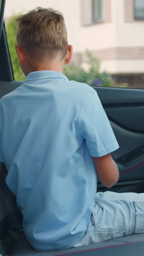 Side view of good-looking smiling blond teen boy which sits down in auto's backs Stock Footage 329435098