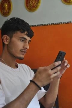 Side view of a good looking young men using phone while sitting indoors 写真素材