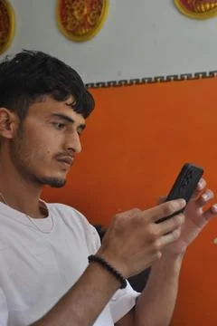 Side view of a good looking young men using phone while sitting indoors Stock Photos