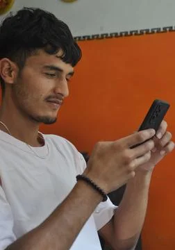 Side view of a good looking young men using phone while sitting indoors Stock Photos