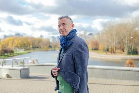 Side view of gorgeous middle-aged man standing near concrete parapet near river Foto stock