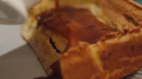 Side View of Gravy Being Poured from Jug on Yorkshire Pudding Toad in the Hole Stock Footage 323875071