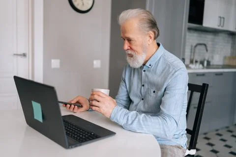Side view of gray-haired mature adult business man working on laptop computer Stock Photos
