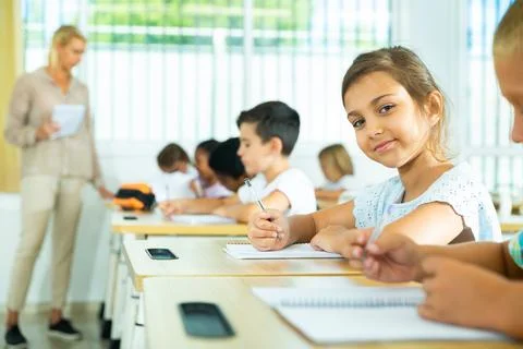 Side view of group of primary school students and positive girl at desk Stock-Fotos