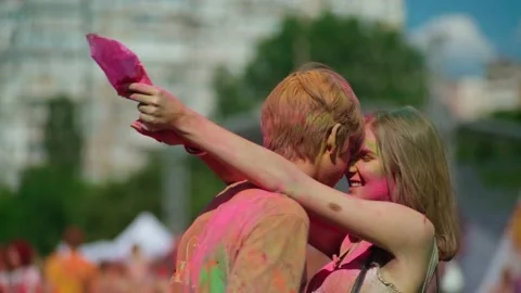 Side view of a guy and a girl covered in Holi colors hugging at the festival. Stock Footage 229775981