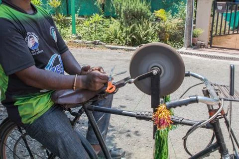 Side view of a guy sharpening tools on his bicycle Stock Photos