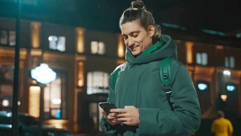 Side view of a guy standing on the street and writing a message on a mobilephone Stock Footage 231690752