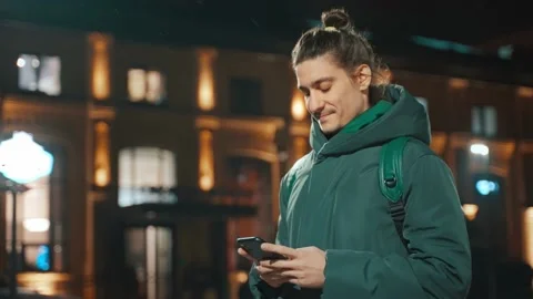 Side view of a guy standing on the street and writing a message on a mobilephone Stock Footage 231897846