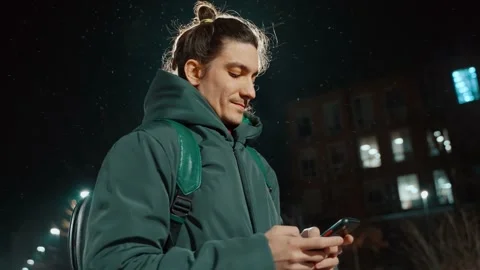 Side view of a guy standing on the street and writing a message on a mobilephone Stock Footage 232608987