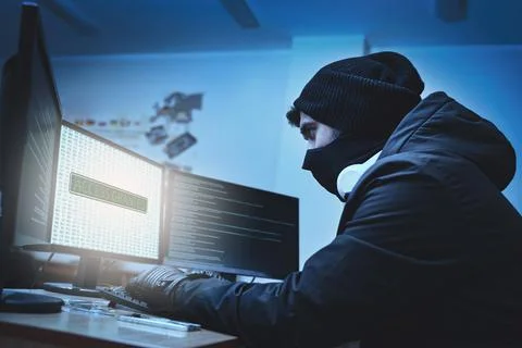 Side view of a hacker hacking into corporate data servers from his undergroun Stock Photos
