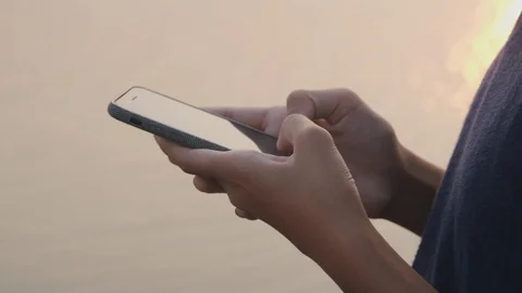 Side view. Hand of a girl using a smartphone on the beach Stock Footage 125590465