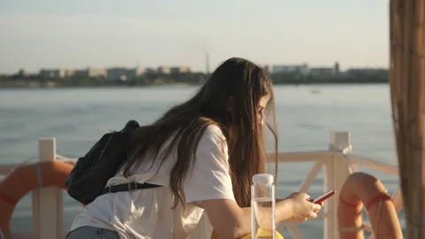 Side view. Hand of girl using smartphone on the terrace by the lake, typing Stock Footage 160053939