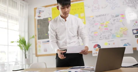 Side view hand held of of Asian businessman looking at laptop and writing  Stock Footage 201920520