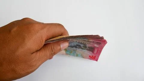 Side View of Hand Holding a Thick Stack of Indonesian Rupiah Banknotes Stock Photos
