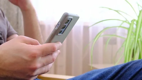 Side view. Hand of man using smartphone in the living room at home, typing Video stock 231697257
