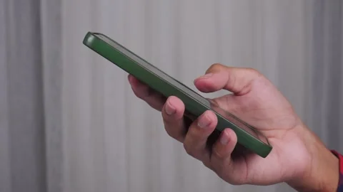 Side view of hand using phone with curtain in the background Stock Footage 277013528