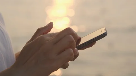 Side view. Hand of woman using smart phone on beach at sunset or sunrise. Stock Footage 124573177