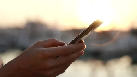 Side view of the hand of a woman using a smartphone on the beach at sunset or Stock-Footage 159273043
