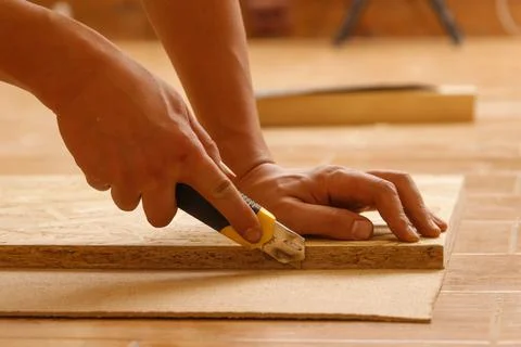 Side view of the hands of a Carpenter who cuts fiberboard while making furniture Stock Photos