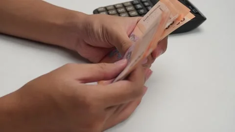 Side view of hands counting money Indonesian rupiah with calculator Stock Footage 276519122