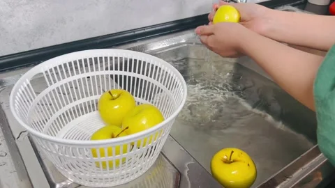 Side View of Hands Placing Fresh Yellow Apples into White Basket Stock Footage 338161508