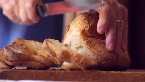 Side view of hands slicing bread with a knife, capturing precise cuts Stock Footage 285662870