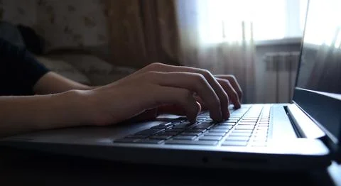 Side view hands typing on a laptop, a person writing an email, working from.. Stock Photos
