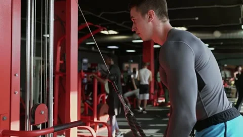 Side view of handsome athletic man trains triceps on machine at gym Video stock 143521861