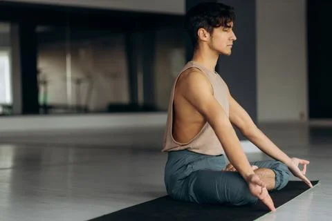 Side view of handsome calm focused guy sitting on floor meditating relaxation Stock Photos