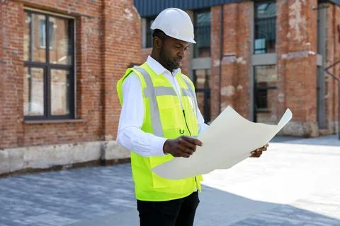 Side view of the handsome engineer wearing white helmet and holding building Stock Photos