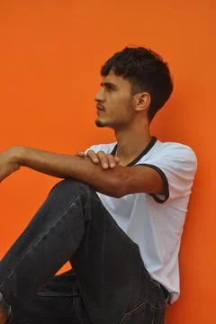 Side view of a handsome Indian guy looking sideways while sitting outside Foto stock