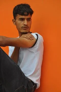 Side view of a handsome Indian guy looking sideways while sitting outside Stock Photos