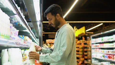 Side view of handsome indian man buying milk. A man shopping dairy product in Stock Footage 251824444