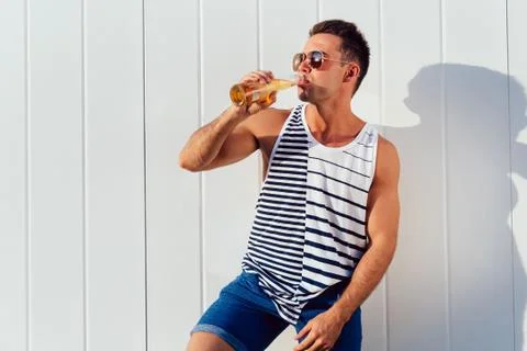 Side view of handsome man drinking a beer, outdoors. Stock Photos