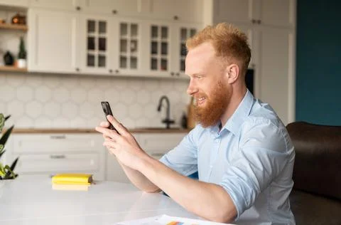 Side view of handsome red haired caucasian man using smartphone Stock Photos