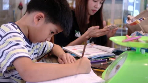 Side view handsome young boy doing homework with mom Stock Footage 162812676