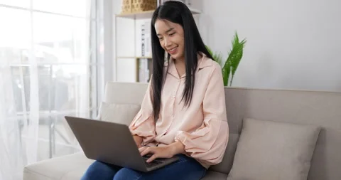 Side view of Happy asian young woman is chatting on a laptop while sitting  스톡 동영상 200862690