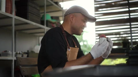 The side view of happy man wearing gloves and apron for cactus gardening. Video stock 268433668