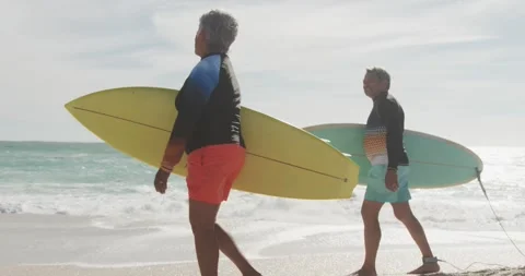 Side view of happy senior hispanic couple walking on beach with surfboards Stock Footage 340256324