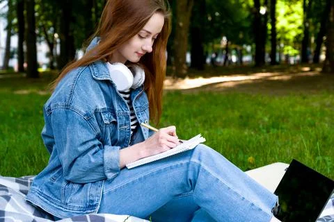 Side view on a happy student taking down notes. Distant education concept. Un Stock Photos
