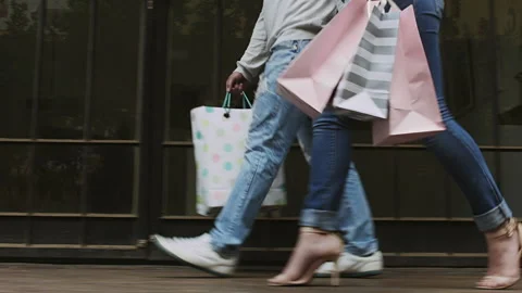Side view of  happy young couple walking with shopping bags and holding hands. S Stock Footage 199632129