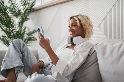 Side view on happy young student african american girl at home using phone for Stock Photos