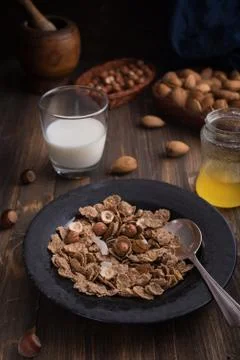 Side view of healthy breakfast with nuts and corn flakes on brown rustic back Stock Photos